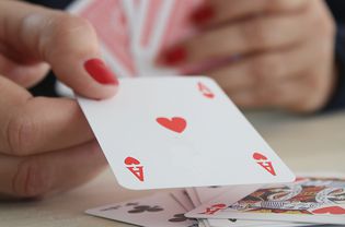 Womans hand holding an ace of hearts playing card