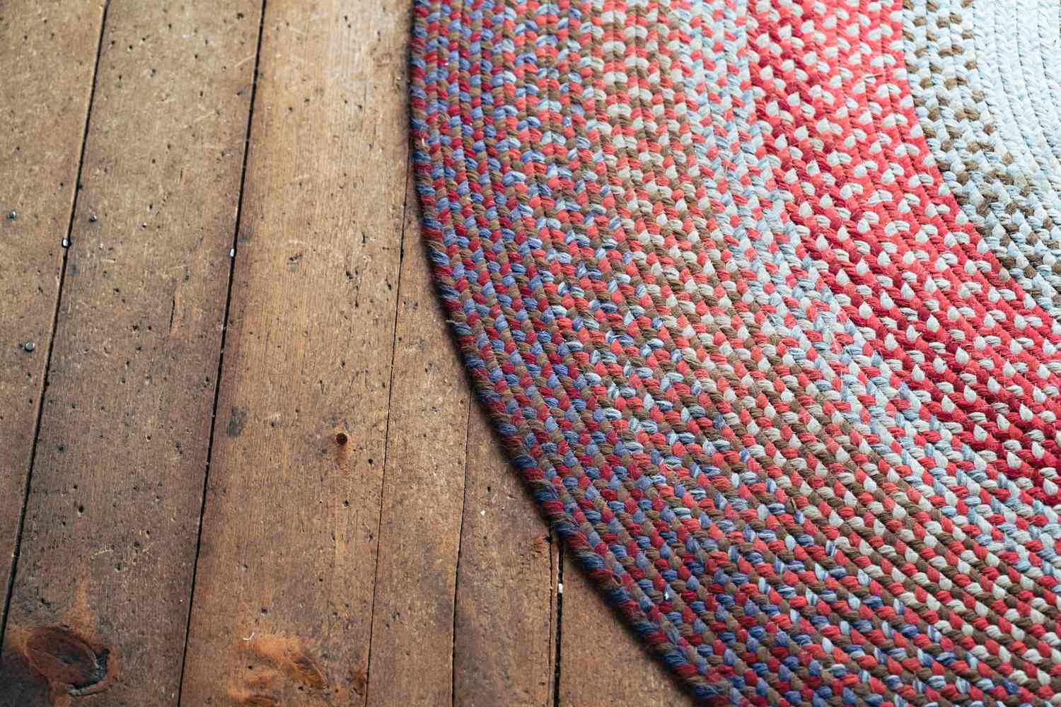 Colorful round braided rug on hardwood floor