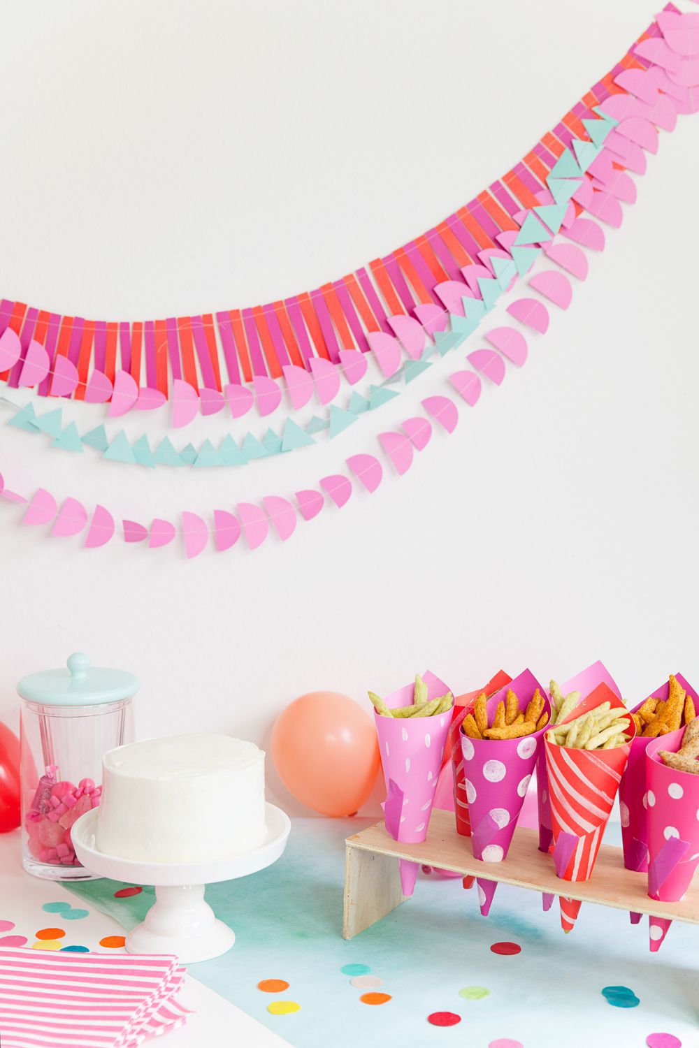 粉红色和蓝色的纸花环，纸聚会袋和白色蛋糕。
