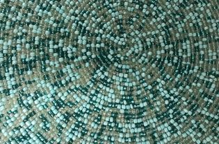 Part of a circular placemat made of plastic beads