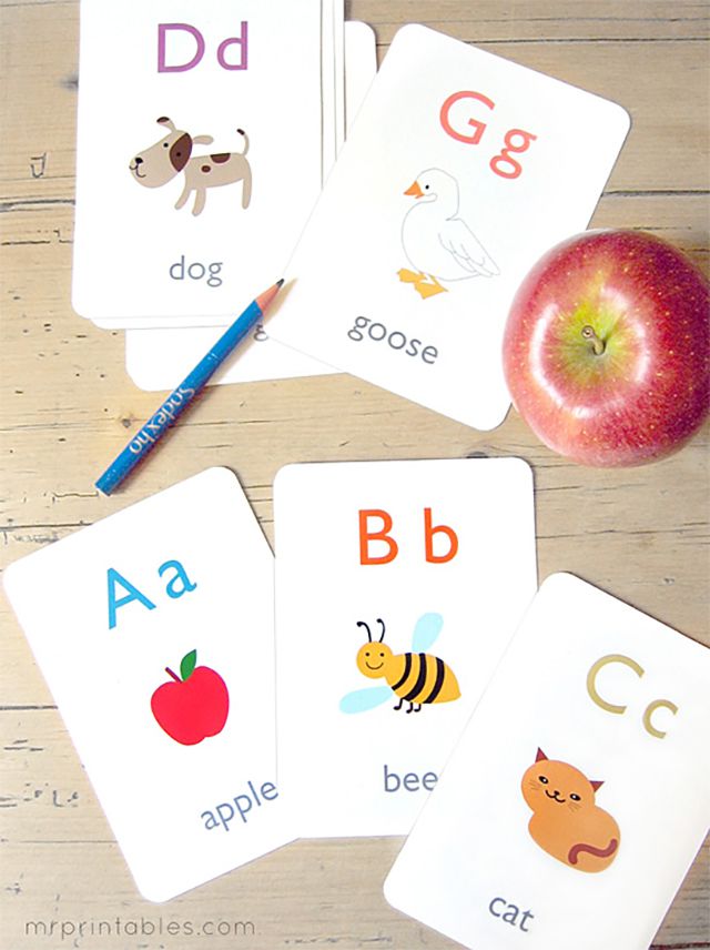 字母卡片躺在一个表和一个苹果和铅笔