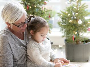 奶奶看着孙女在圣诞树前画画