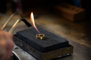 金戒指在珠宝厂用气体火焰退火，在暗背景中复制空间，选择焦点，景深窄