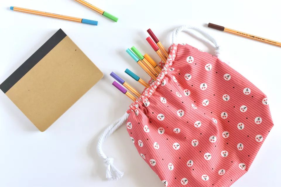 一个粉红色的花束袋，里面有铅笔和笔记本
