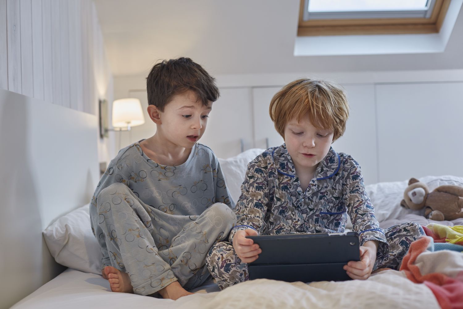 穿着睡衣的男孩在床上使用平板电脑