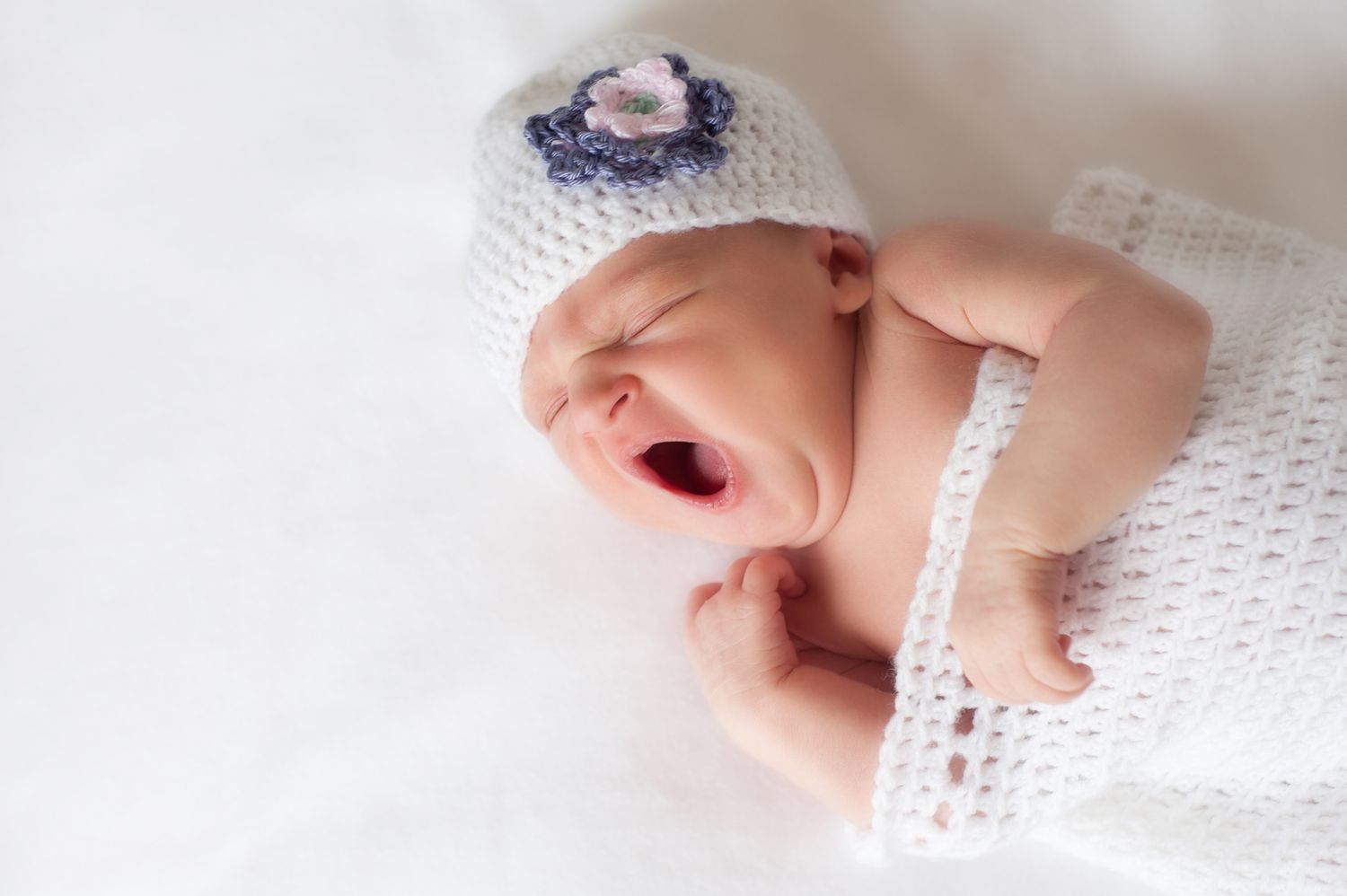 刚出生的女婴在钩针编织的衣服打呵欠