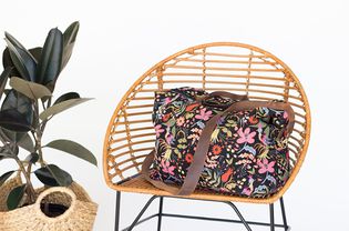 一个带花的行李袋放在藤椅上