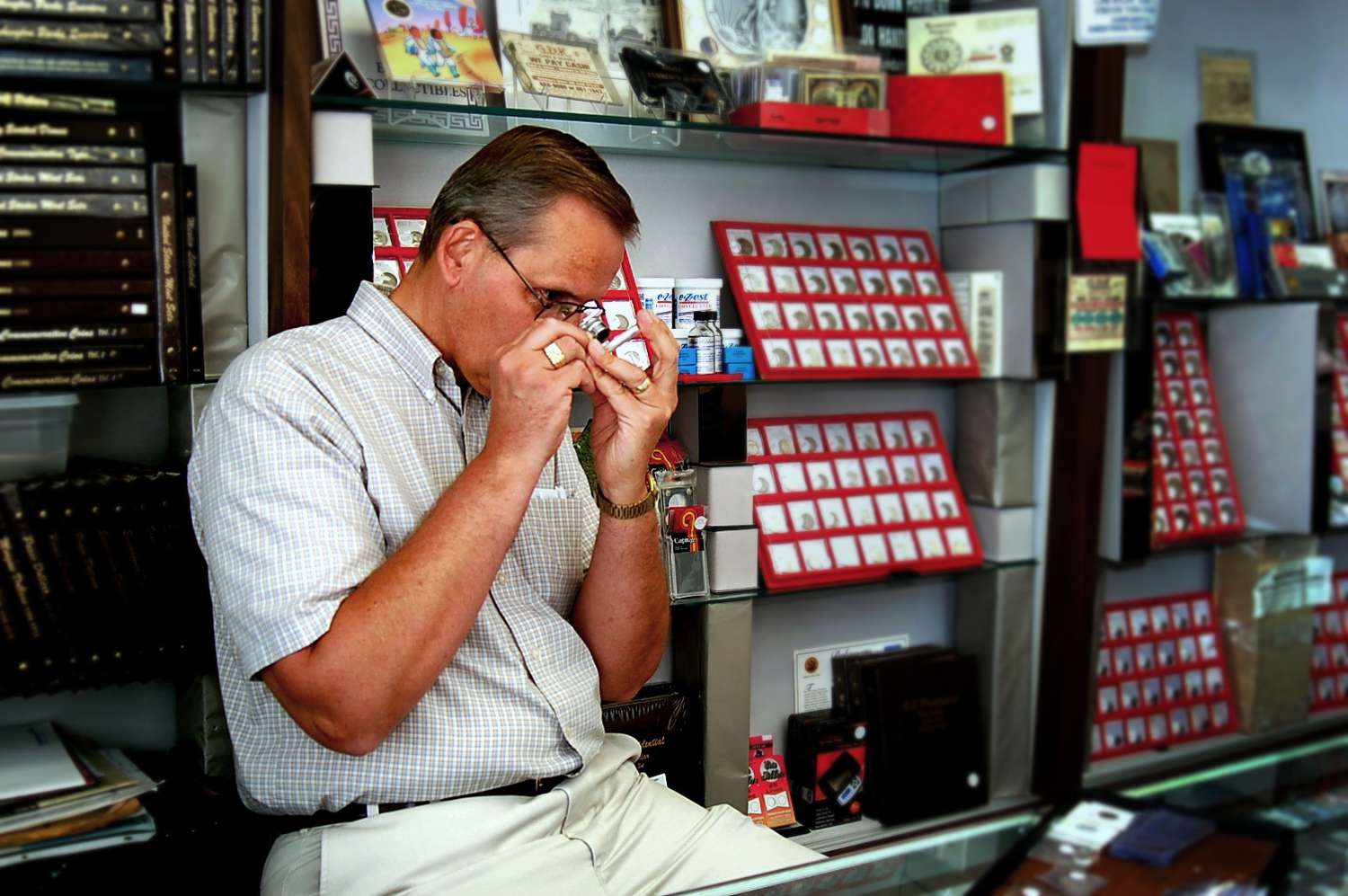 一个钱币商在他的钱币店里检查一枚钱币。