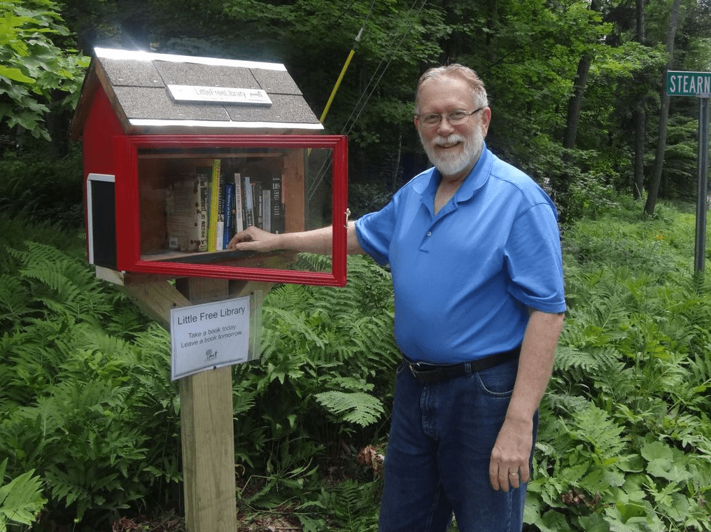 一个男人站在一个免费的小图书馆旁边