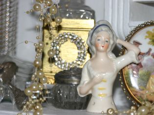Vintage pincushion half doll on a shelf with costume jewelry.