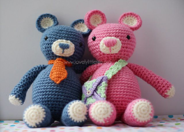 一个蓝色和一个粉红色的钩针熊坐在对方。