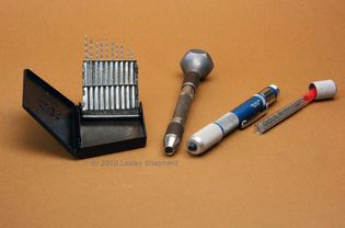 A set of miniature drills in a drill index, along with a revolving head pin vice and a mini drill.