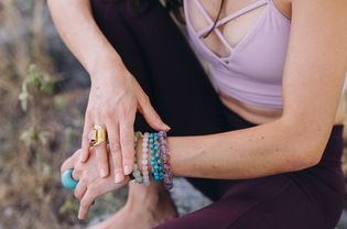 Female hands touching each other wearing several rings and bracelets from precious stones and yoga pants