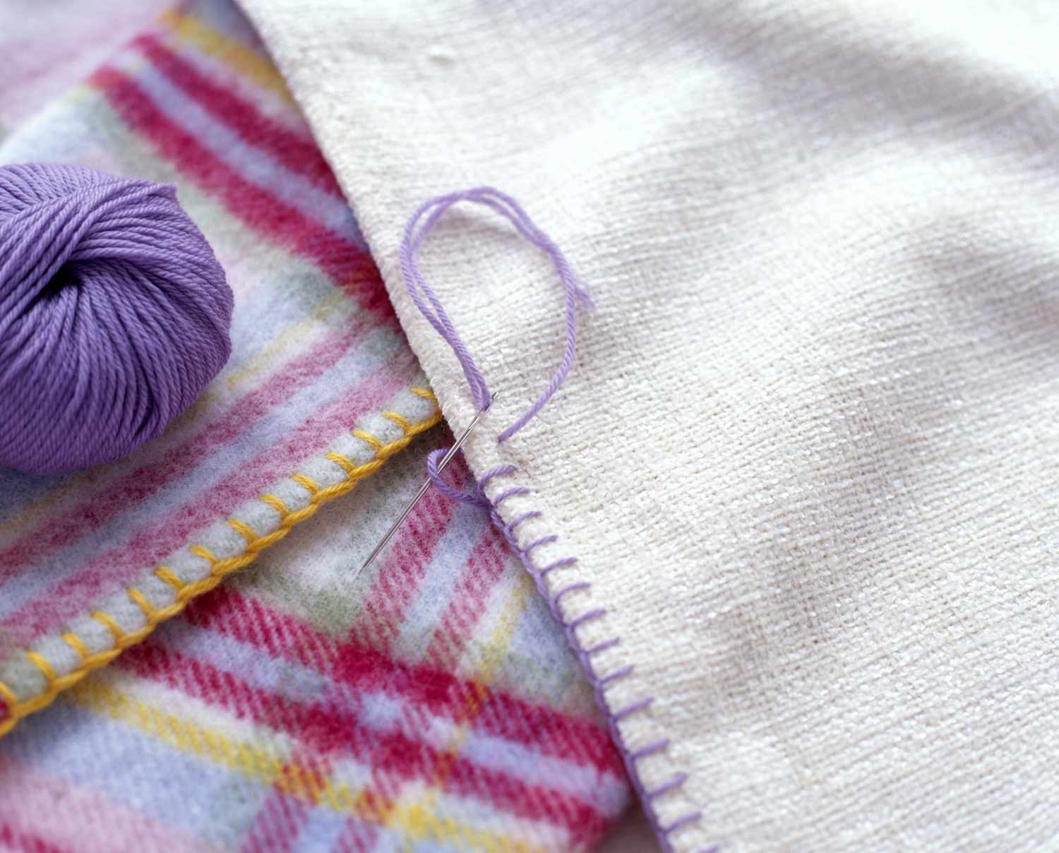 毯缝装饰织物边缘，附近有紫色毛线团