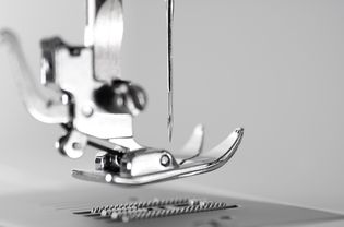 Close-up view of sewing machine pressure foot and needle.