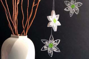 paper quilled daisies hanging next to a vase