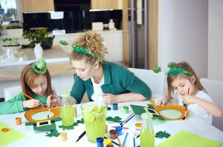 A mom and her children creating St. Patrick's Day crafts