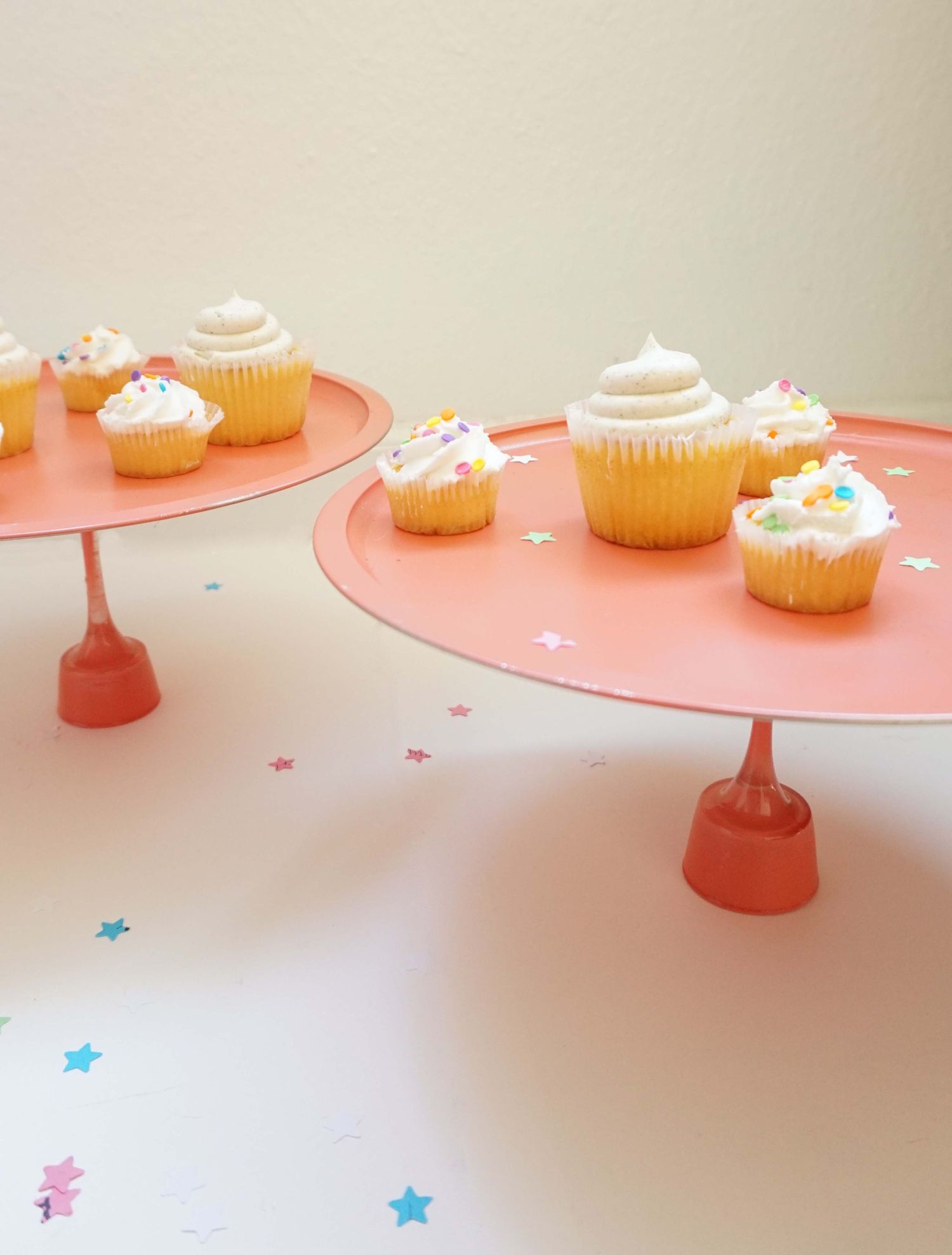 粉色纸杯蛋糕DIY摊，上面有香草纸杯蛋糕和五彩纸屑。